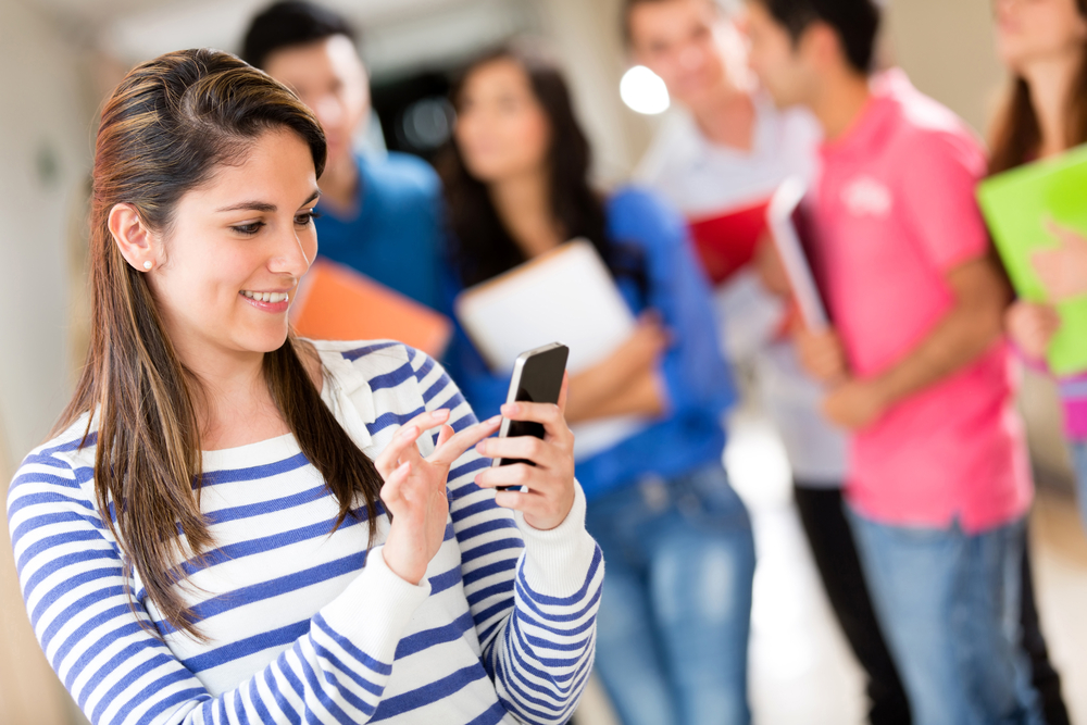 Female student texting from her cell phone at the university-1