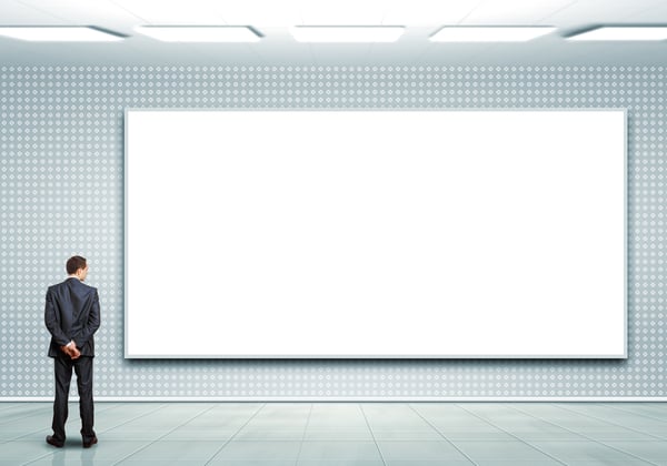 Business person standing near a white blank billboard